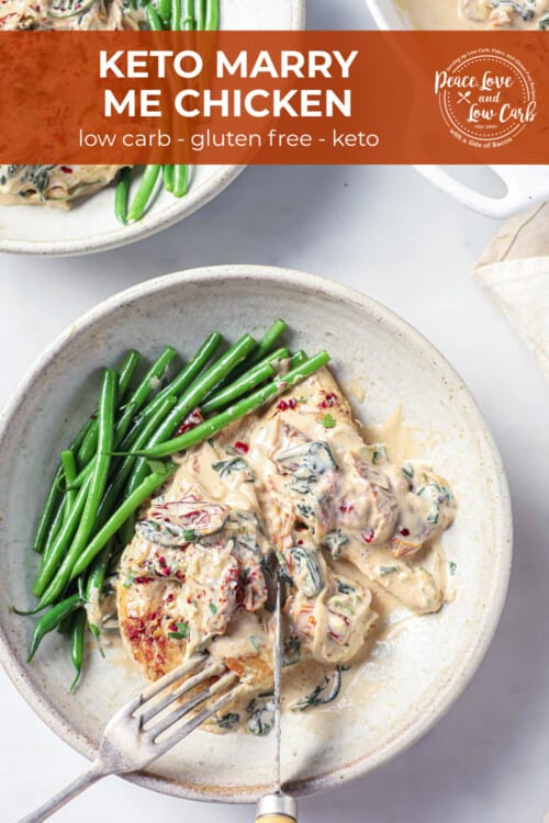 A white ceramic bowl with a chicken breast, topped with a sun-dried tomato cream sauce, with green beans on the side.